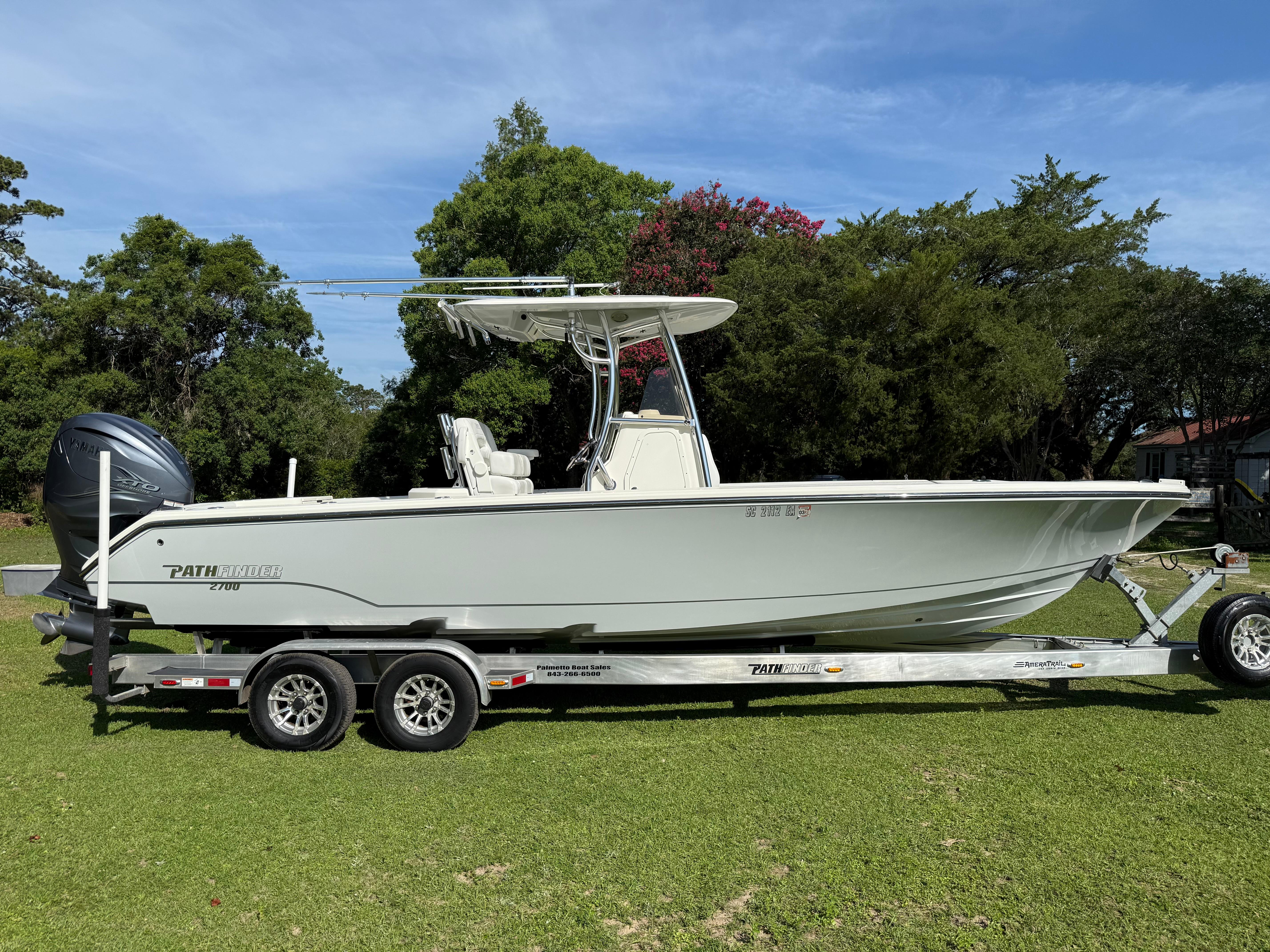 Pathfinder 2700 Open 2022 Pathfinder 2700 Open boat on trailer, parked on grass with trees in background.