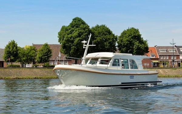 Linssen Grand Sturdy 35 Sedan 2021 Linssen Grand Sturdy 35 Sedan cruising on a calm river near a residential area.
