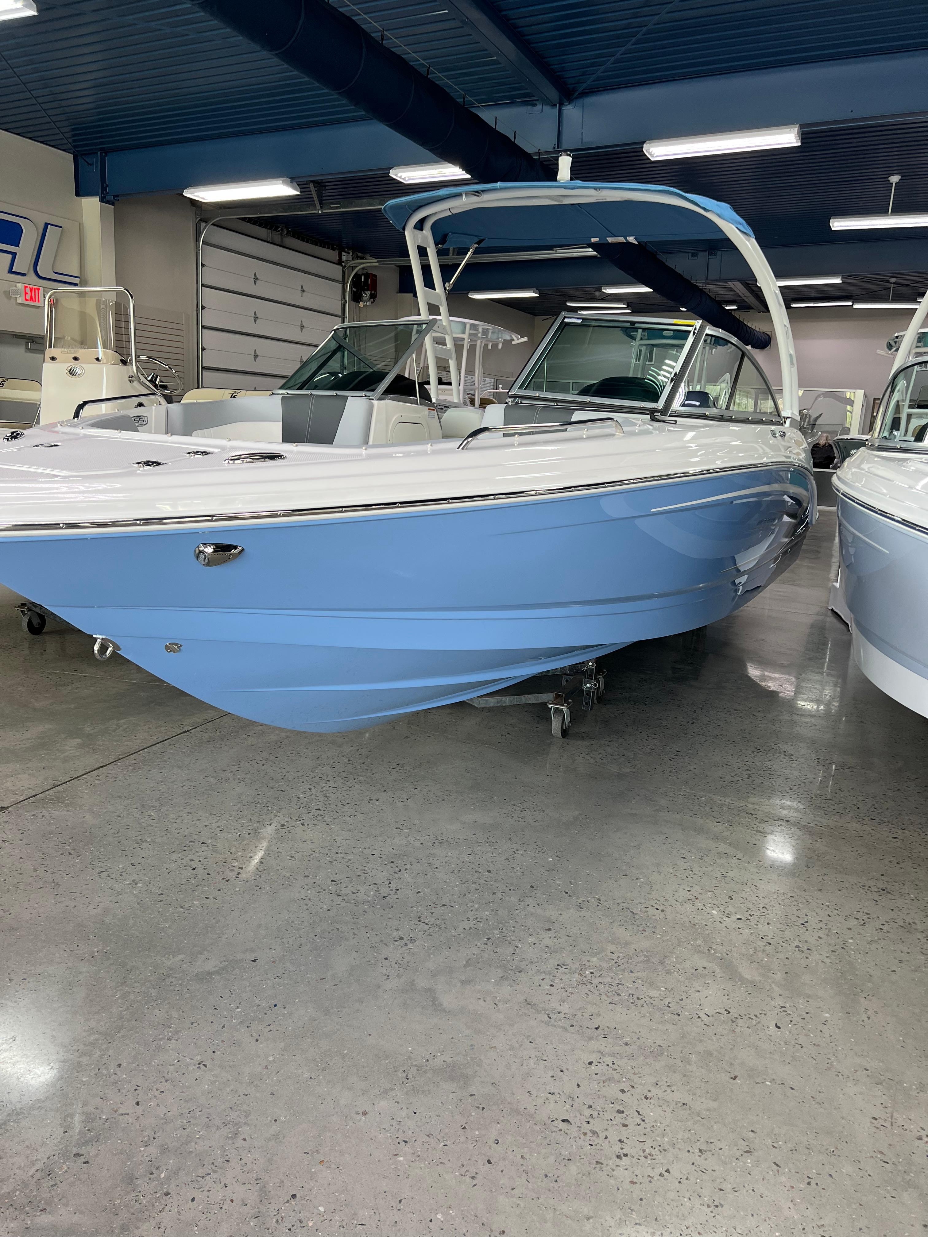 Chaparral 23 SSi OB 2023 Chaparral 23 SSi OB boat in showroom, featuring sleek blue and white design.
