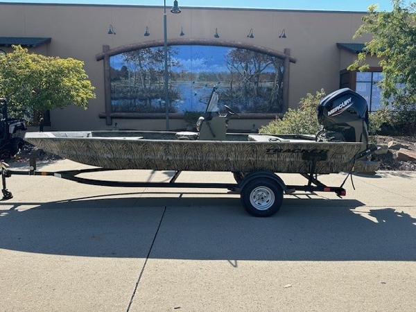 Tracker Grizzly 1860 CC 2025 Tracker Grizzly 1860 CC boat on trailer, outdoors, with Mercury engine.