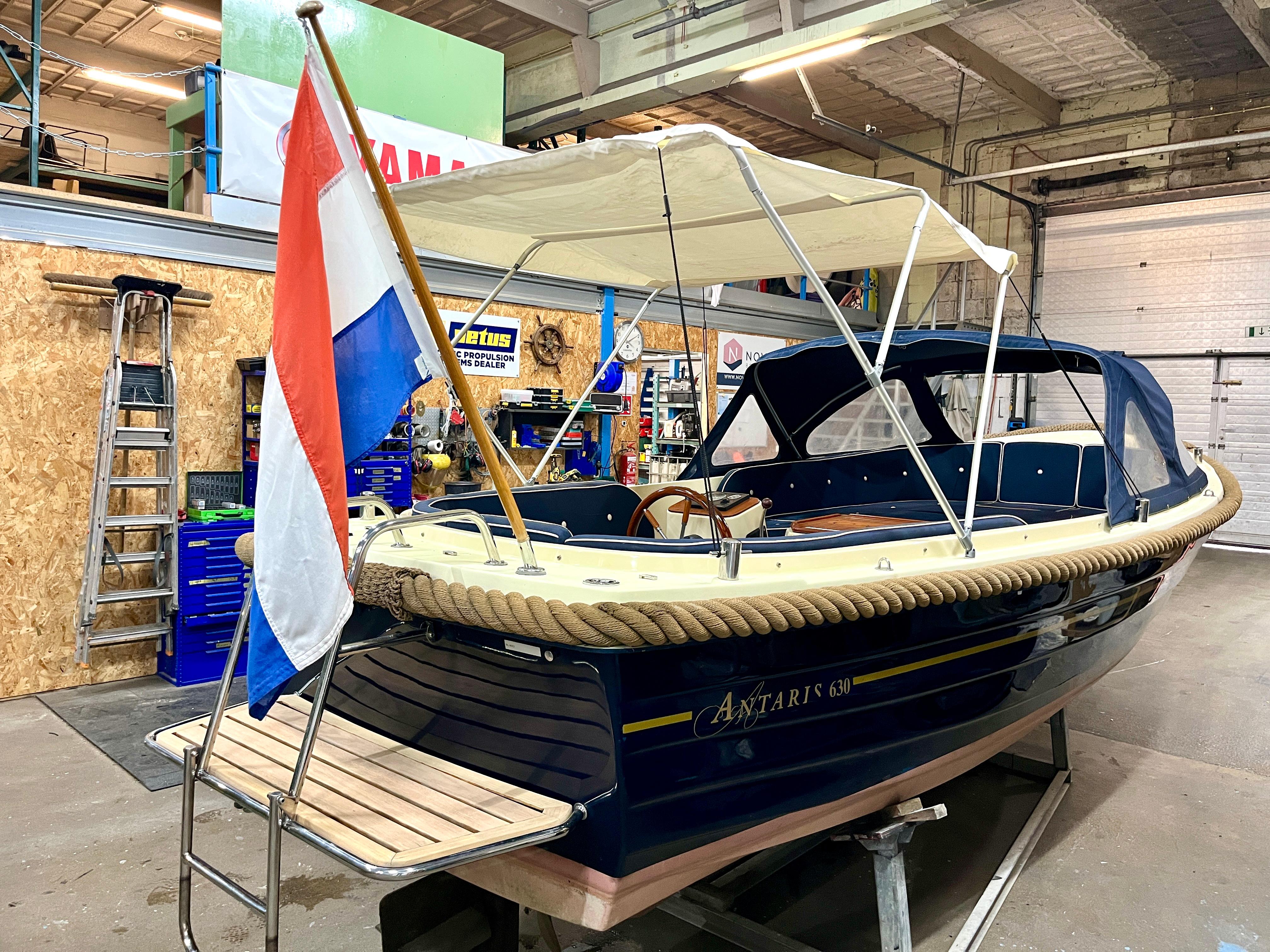 Antaris 630 | Vetus 27pk | Blauw | zwemplateau Antaris 630 boat with canopy and Dutch flag in a workshop, 2006 model.