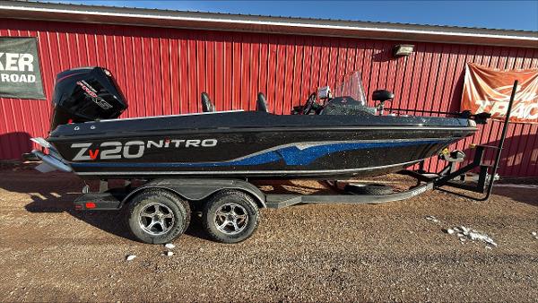 Nitro ZV20 2024 Nitro ZV20 boat on trailer, black with blue accents, parked by red building.