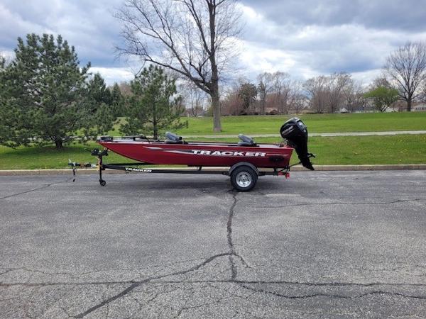 Tracker Panfish 17 2025 Tracker Panfish 17 boat on trailer, parked outdoors with trees in the background.