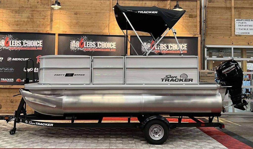 Sun Tracker Party Barge 16 DLX 2026 Sun Tracker PARTY BARGE® 16 DLX pontoon boat displayed indoors on a trailer.