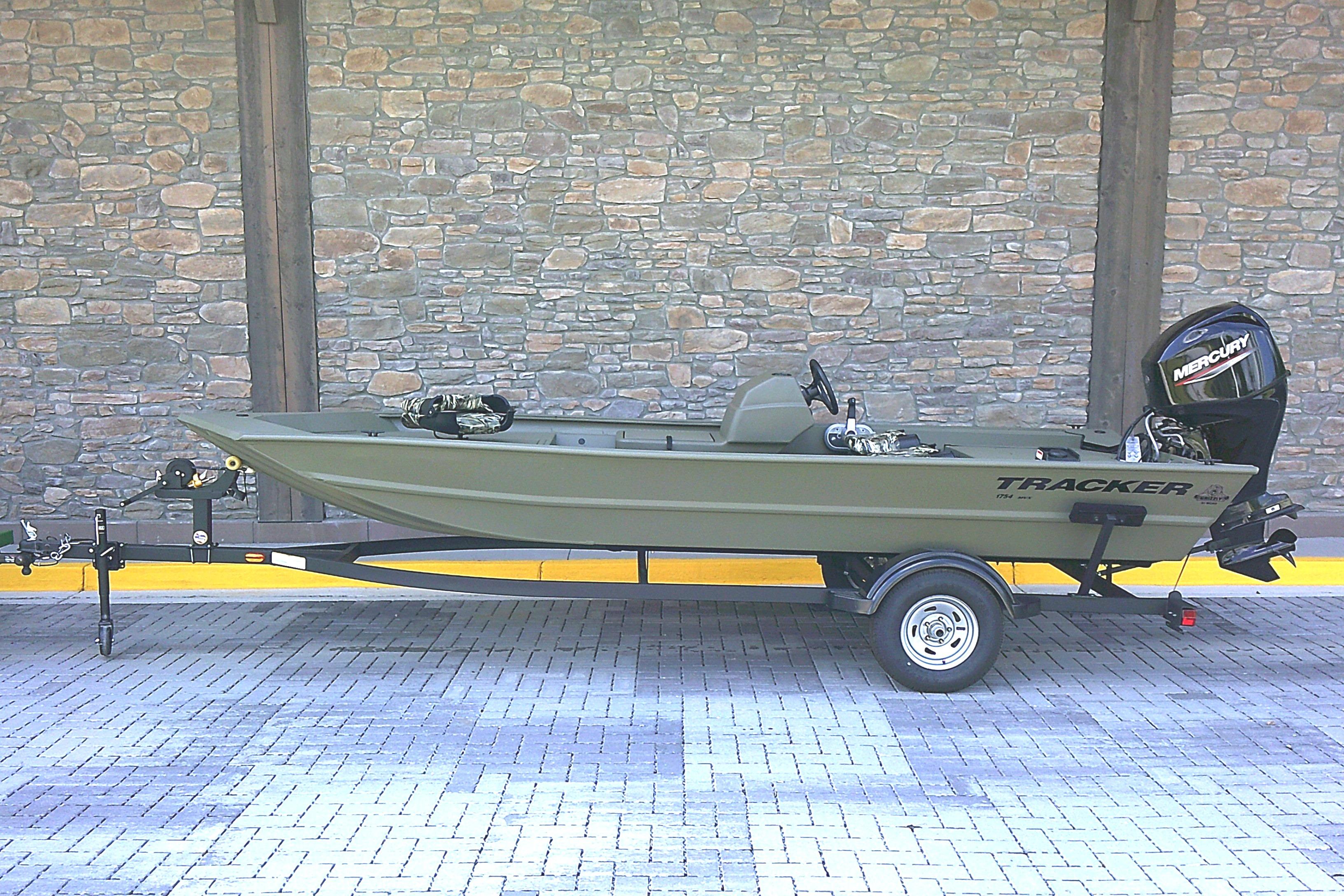 Tracker Grizzly 1754 SC 2026 Tracker Grizzly 1754 SC boat on trailer, parked against stone wall.