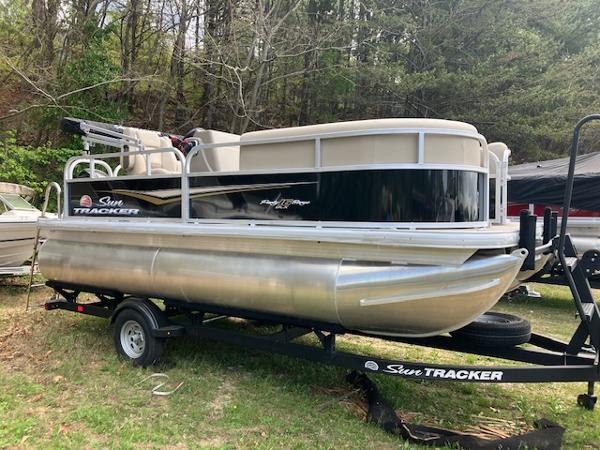 Sun Tracker Party Barge 16 DLX 2025 Sun Tracker Party Barge 16 DLX pontoon boat on trailer, parked outdoors.