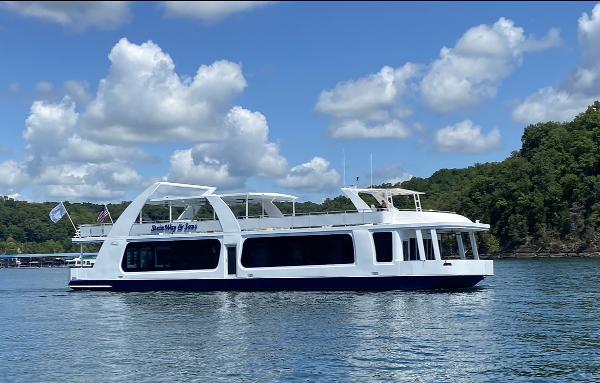 Thoroughbred Houseboat 2020 Thoroughbred houseboat on a lake with blue sky and clouds.