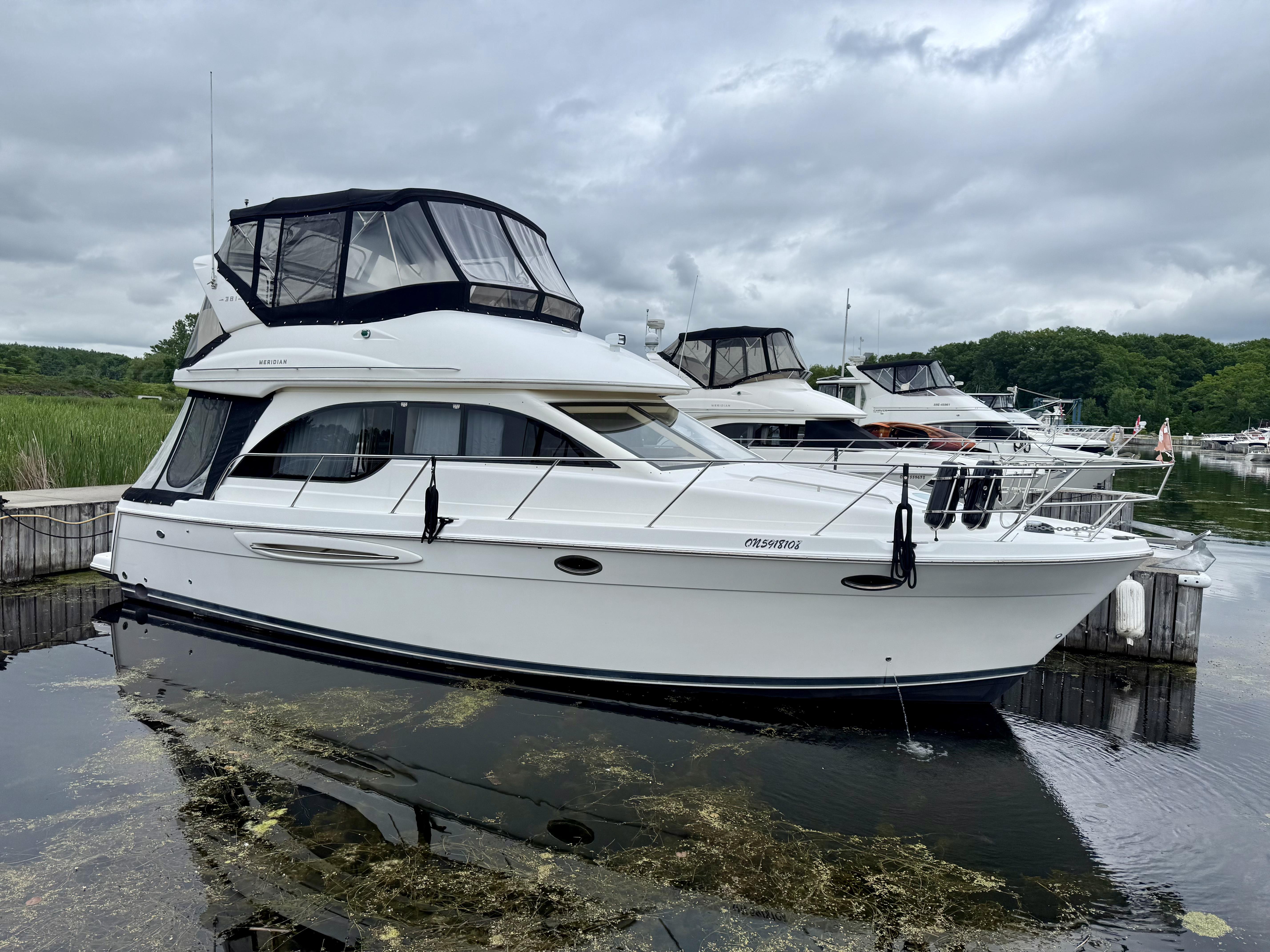 Meridian 381 Sedan 2004 Meridian 381 Sedan yacht docked in a marina, overcast sky, lush greenery in background.