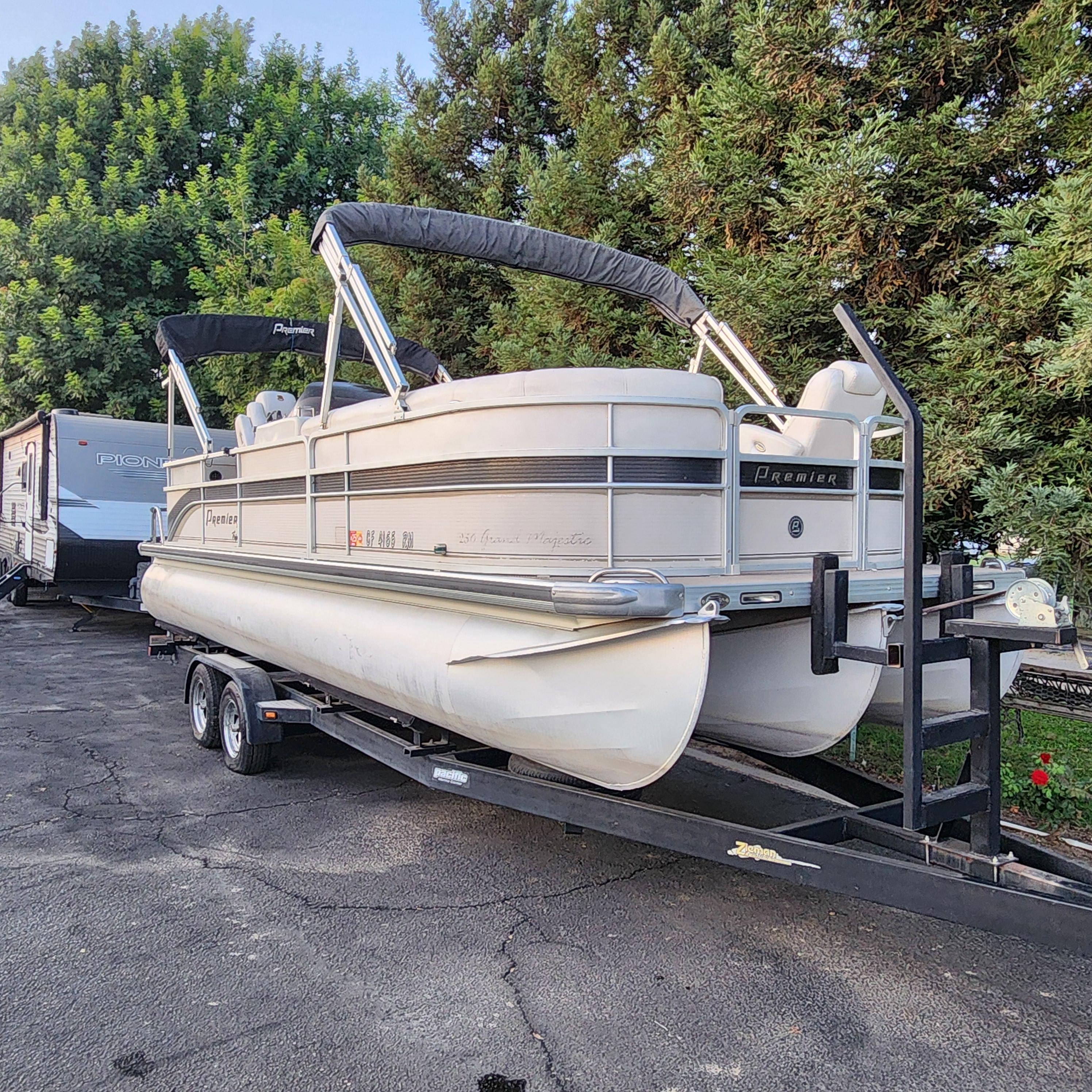 Premier Grand Majestic 2007 Premier Grand Majestic pontoon boat on trailer, parked near trees.