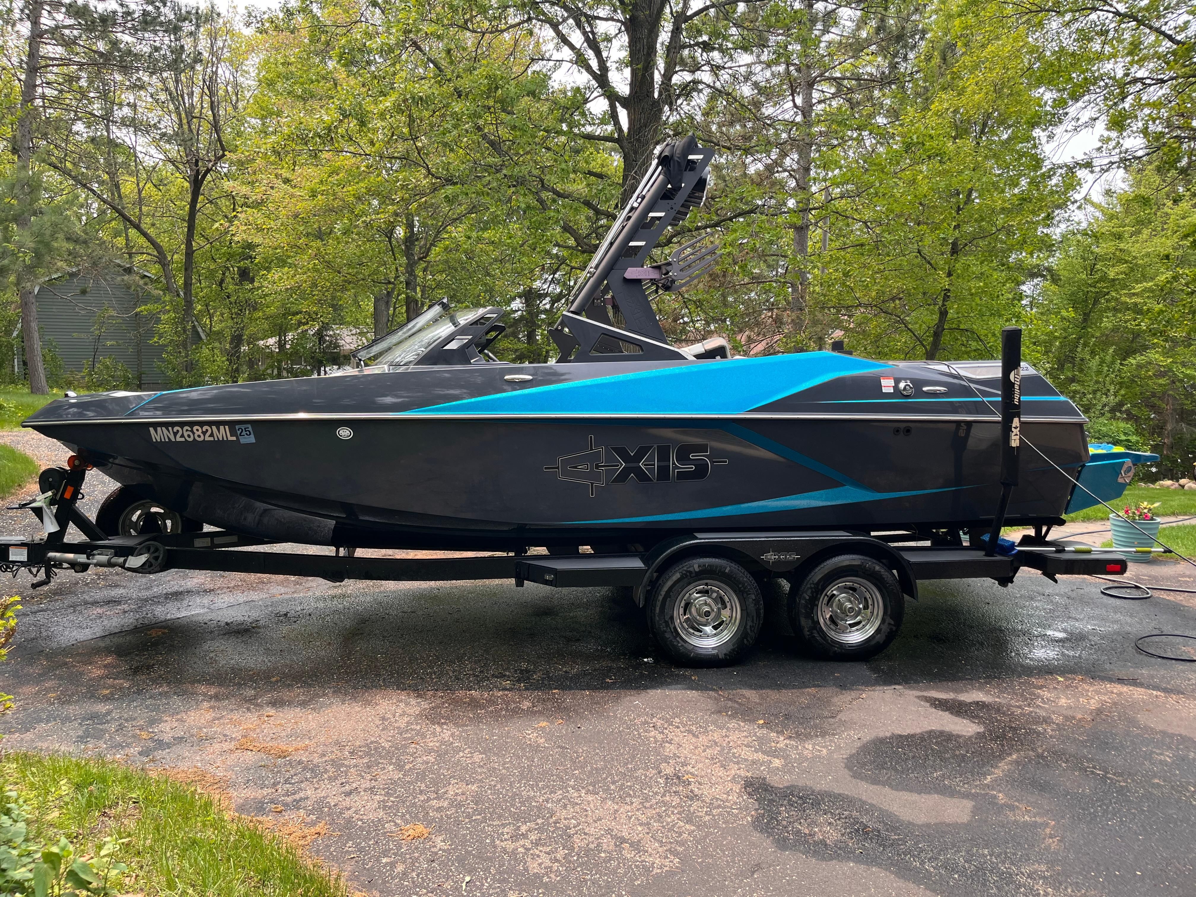 Axis A22 2018 Axis A22 boat on trailer, parked outdoors with trees in the background.