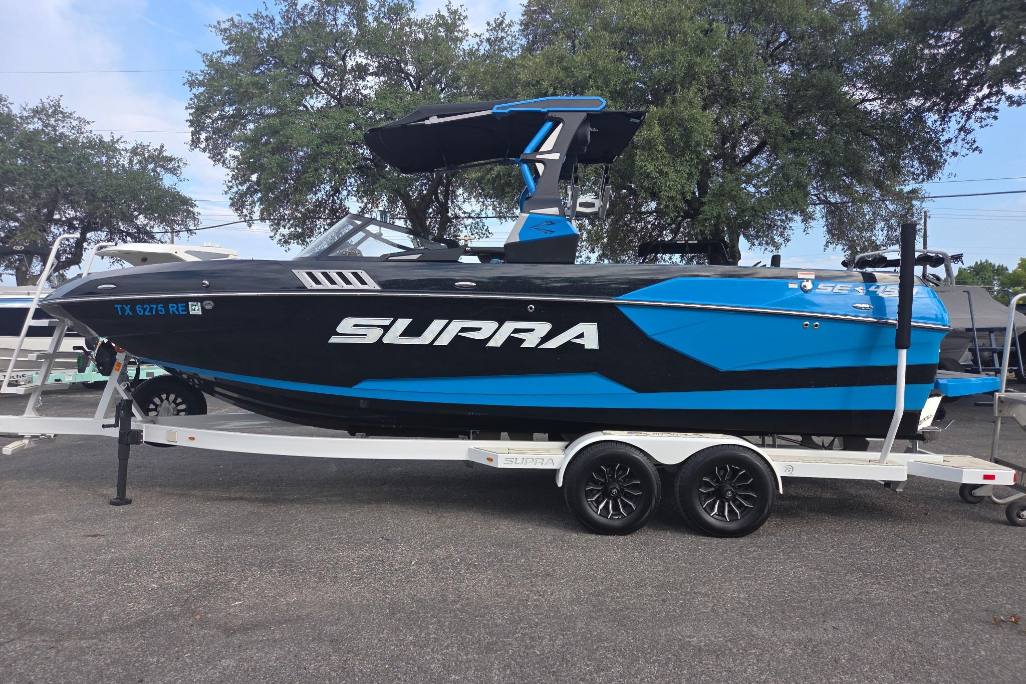 Supra SE 450 2021 Supra SE 450 boat in blue and black on a trailer, parked outdoors.