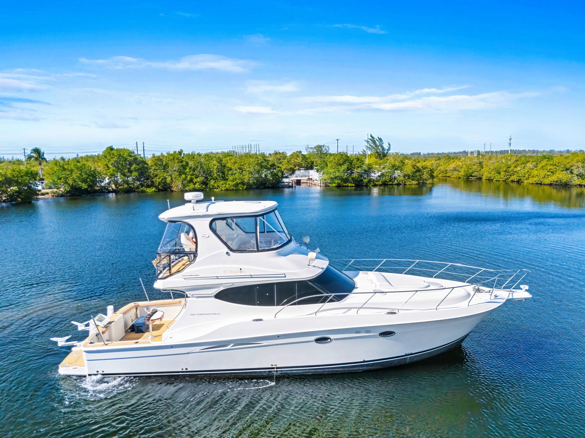 Silverton 45 Convertible 2007 Silverton 45 Convertible yacht cruising on a serene lake under a clear blue sky.