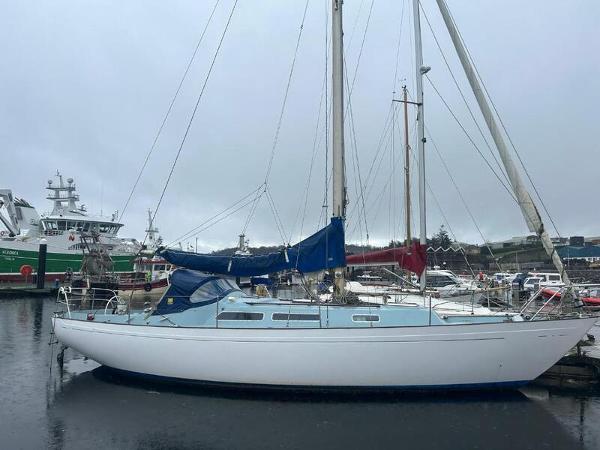 Nicholson 35 1976 Nicholson 35 sailboat docked in a marina on a cloudy day.