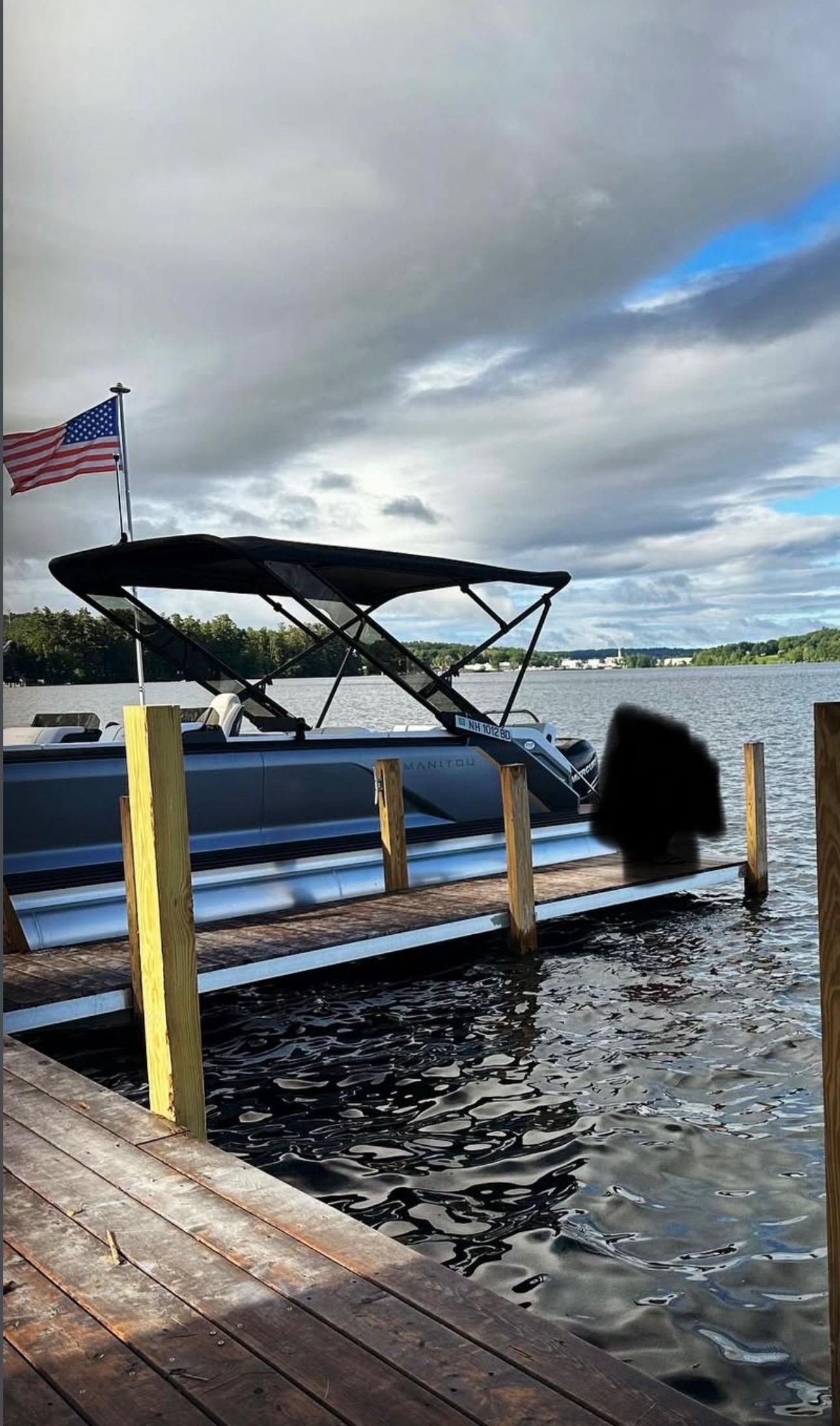 Manitou 26 Explore Switchback 2024 Manitou 26 Explore Switchback pontoon boat docked on a lake under cloudy skies.