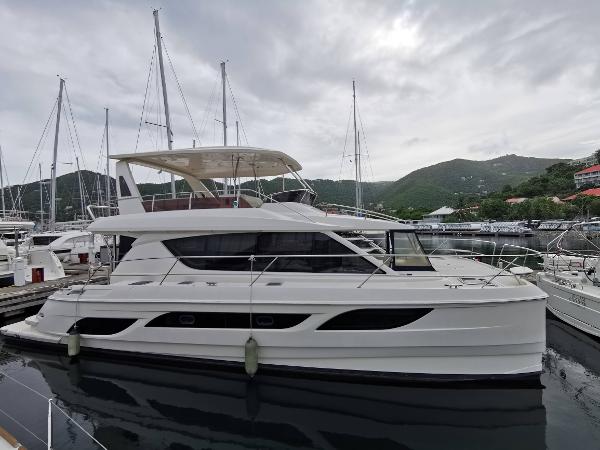 Aquila 48 Aquila 48 yacht, 2016 model, docked in a marina with sailboats and hills in the background.