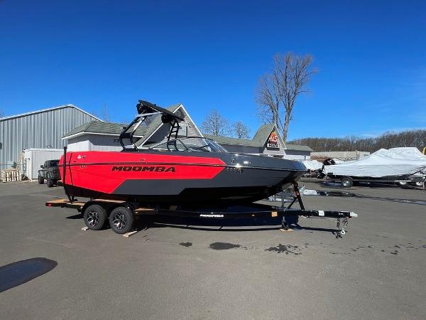 Moomba Max 2025 Moomba Max boat in red and black on trailer, parked outdoors.