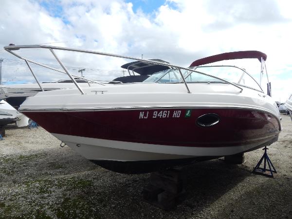 Chaparral 225 SSi 2013 Chaparral 225 SSi boat with red and white hull, docked on land.