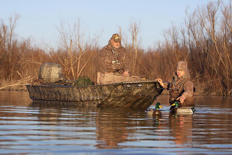 War Eagle 648 Ldv Two hunters in camo with War Eagle 648LDV boat, setting duck decoys in water.