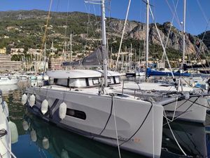 Excess 11 2023 Excess 11 catamaran docked in a scenic marina with mountainous backdrop.