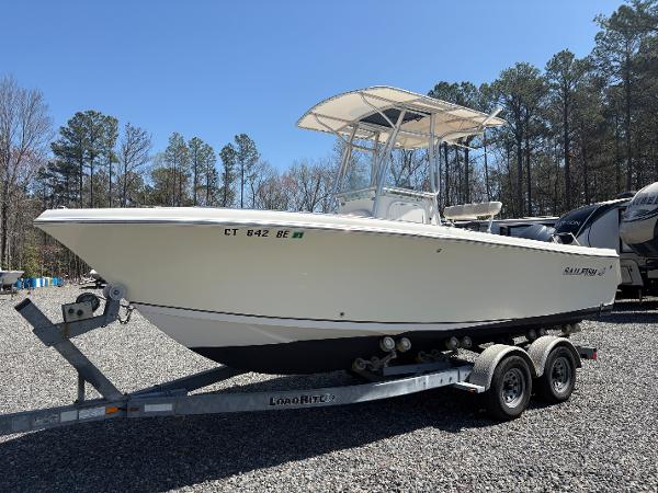 Sailfish 218 CC 2011 Sailfish 218 boat on trailer, parked outdoors, surrounded by trees and RVs.
