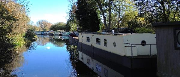Houseboat Static Barge Style Hull Houseboat on tranquil canal, surrounded by trees, featuring a 2004 Static Barge Style Hull.