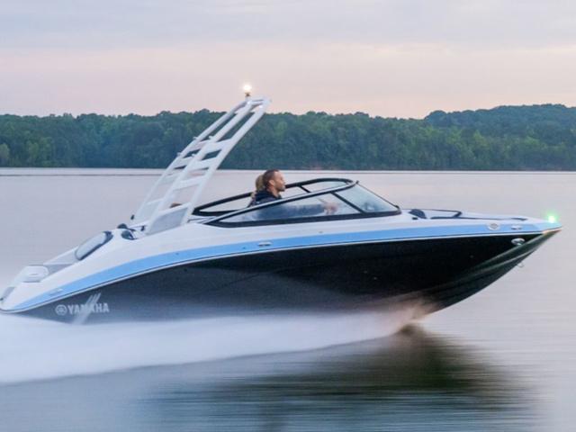 Yamaha Boats 195S 2025 Yamaha Boats 195S speeding on a calm lake with lush green forest backdrop.