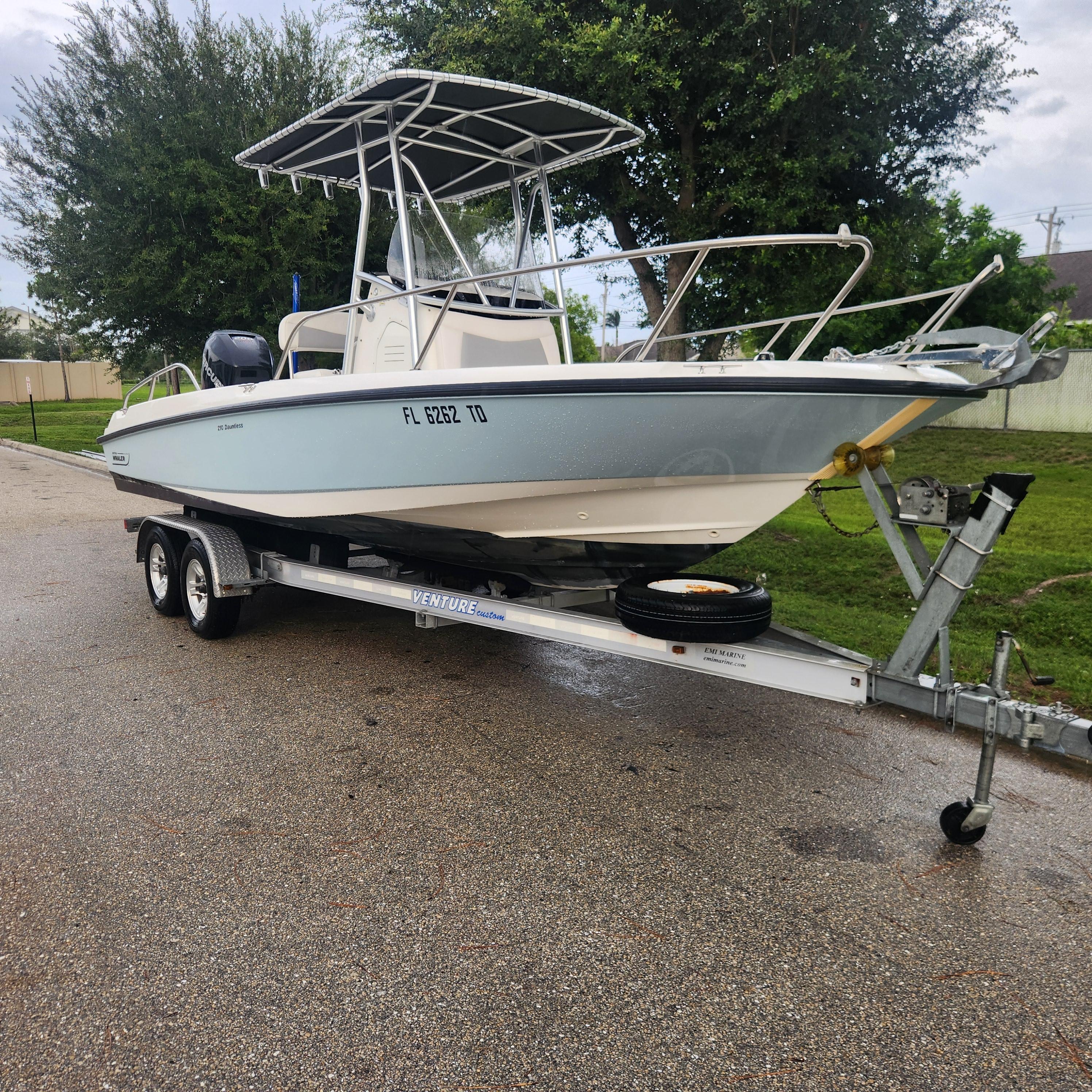Boston Whaler 210 Dauntless 2016 Boston Whaler 210 Dauntless boat on trailer, parked on a wet road.