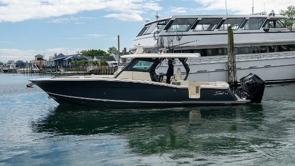 Scout 377 LXF 2025 Scout 377 LXF boat docked in marina, sleek design, calm water, luxury yacht in background.
