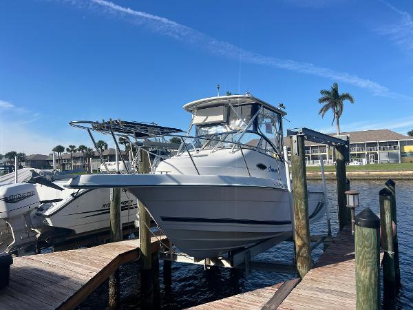 Cobia 230 Walk Around 2002 Cobia 230 Walk Around boat docked by waterfront homes, clear blue sky.