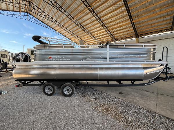 Sun Tracker Party Barge 22 RF XP3 2024 Sun Tracker Party Barge 22 RF XP3 pontoon boat on a trailer under a canopy.