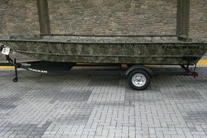 Tracker Grizzly 2072 Utility 2025 Tracker Grizzly 2072 Utility boat on trailer, camo design, parked on brick pavement.