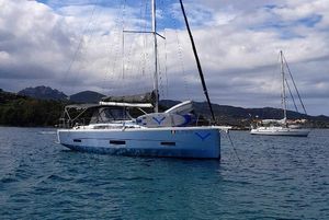 Dufour 390 2019 Dufour 390 sailboat anchored in scenic bay with mountains in background.