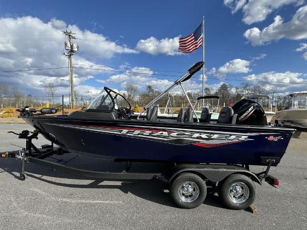 Tracker Targa V-18 Combo 2024 Tracker Targa™ V-18 Combo boat on trailer with American flag in background.