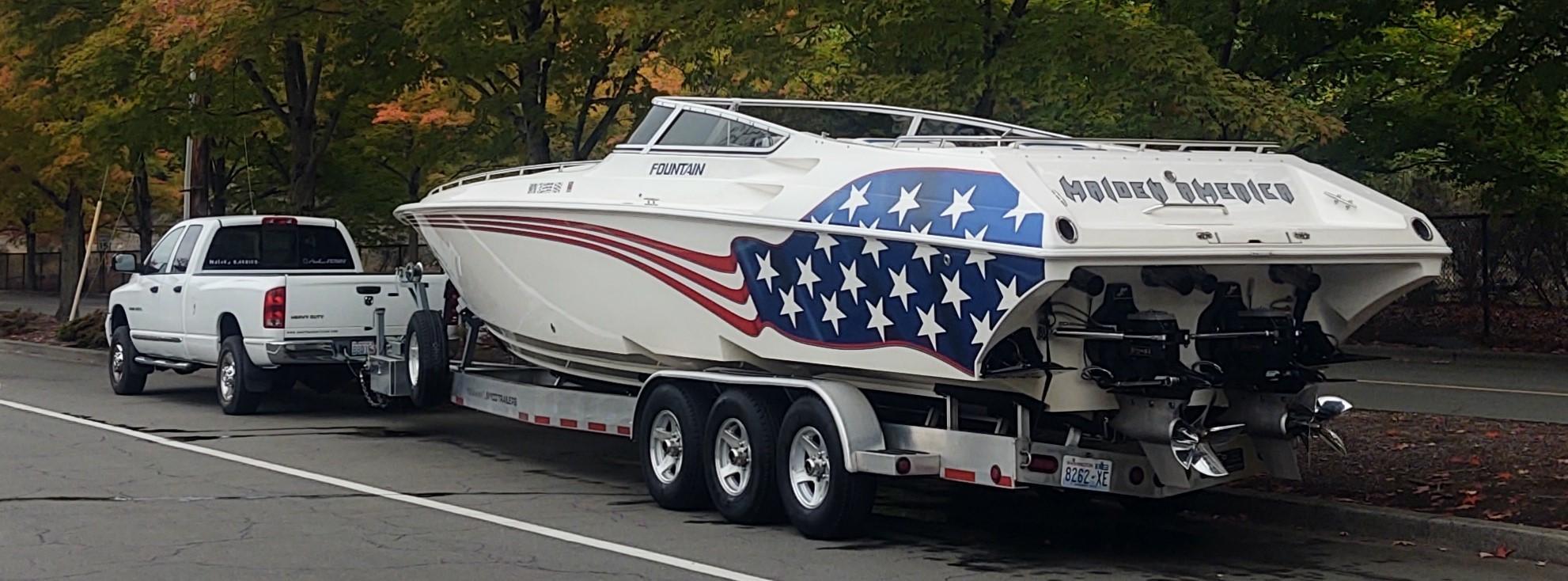 Fountain Lightning 2002 Fountain Lightning boat with American flag design on trailer, parked on a tree-lined street.