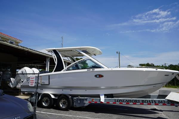 Chaparral 310 OSX 2025 Chaparral 310 OSX boat on trailer, parked outdoors under clear blue sky.