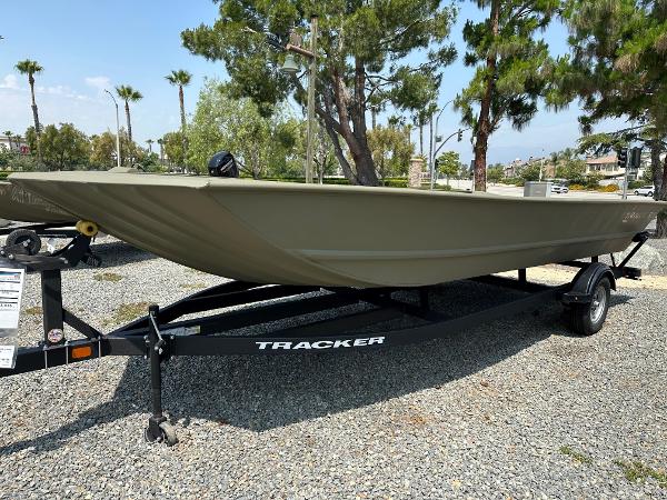 Tracker GRIZZLY 2072 Utility 2025 Tracker GRIZZLY 2072 Utility boat on trailer, parked outdoors, surrounded by trees.