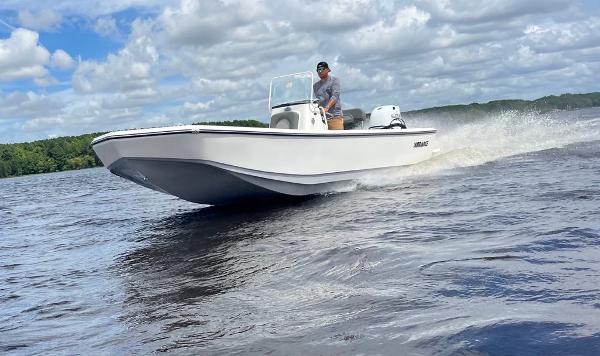Sundance DX22 2025 Sundance DX22 boat cruising on a lake under a cloudy sky.