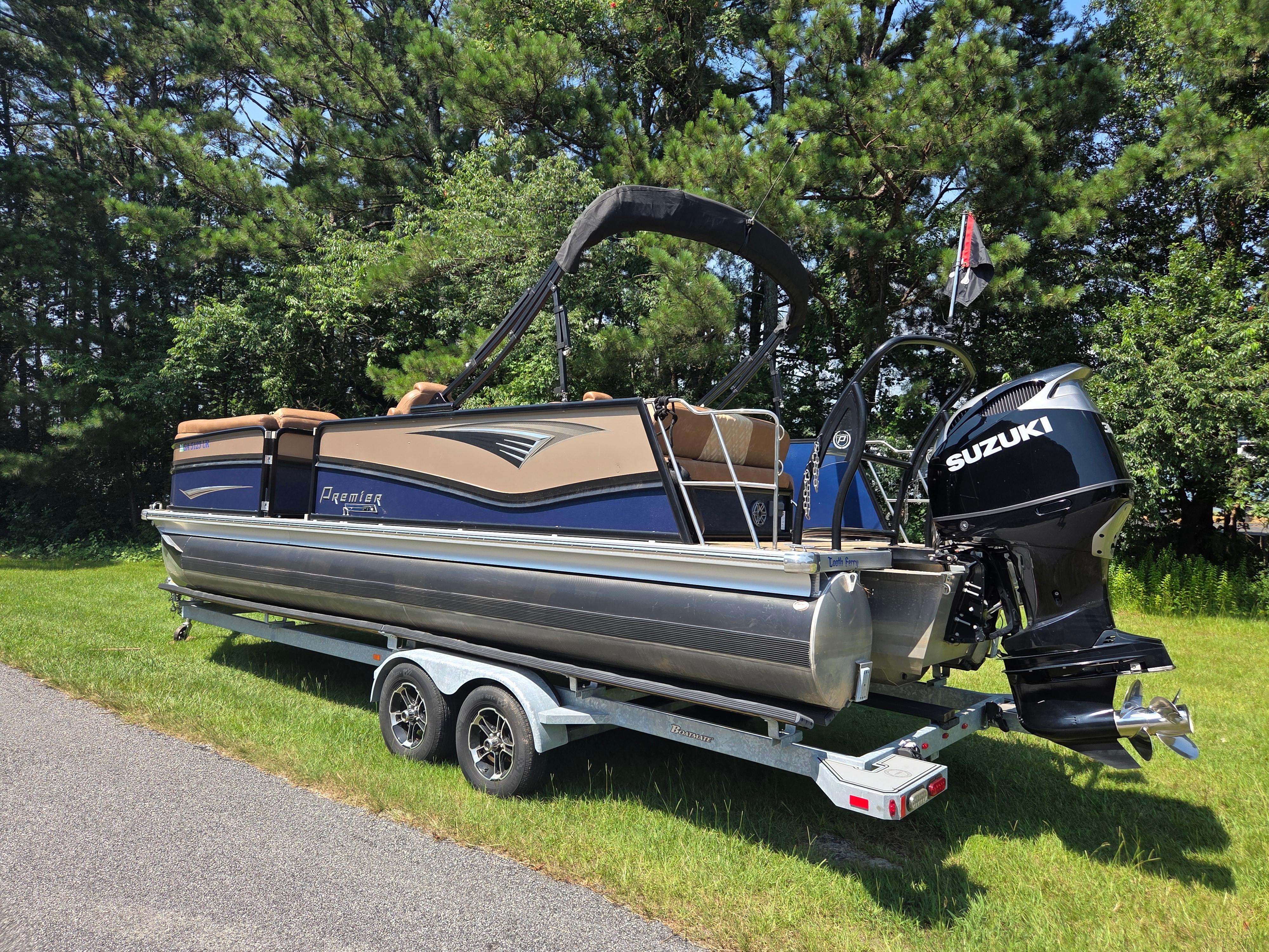 Premier 250 Intrigue RL 2021 Premier 250 Intrigue RL pontoon boat on trailer, featuring Suzuki outboard motor.