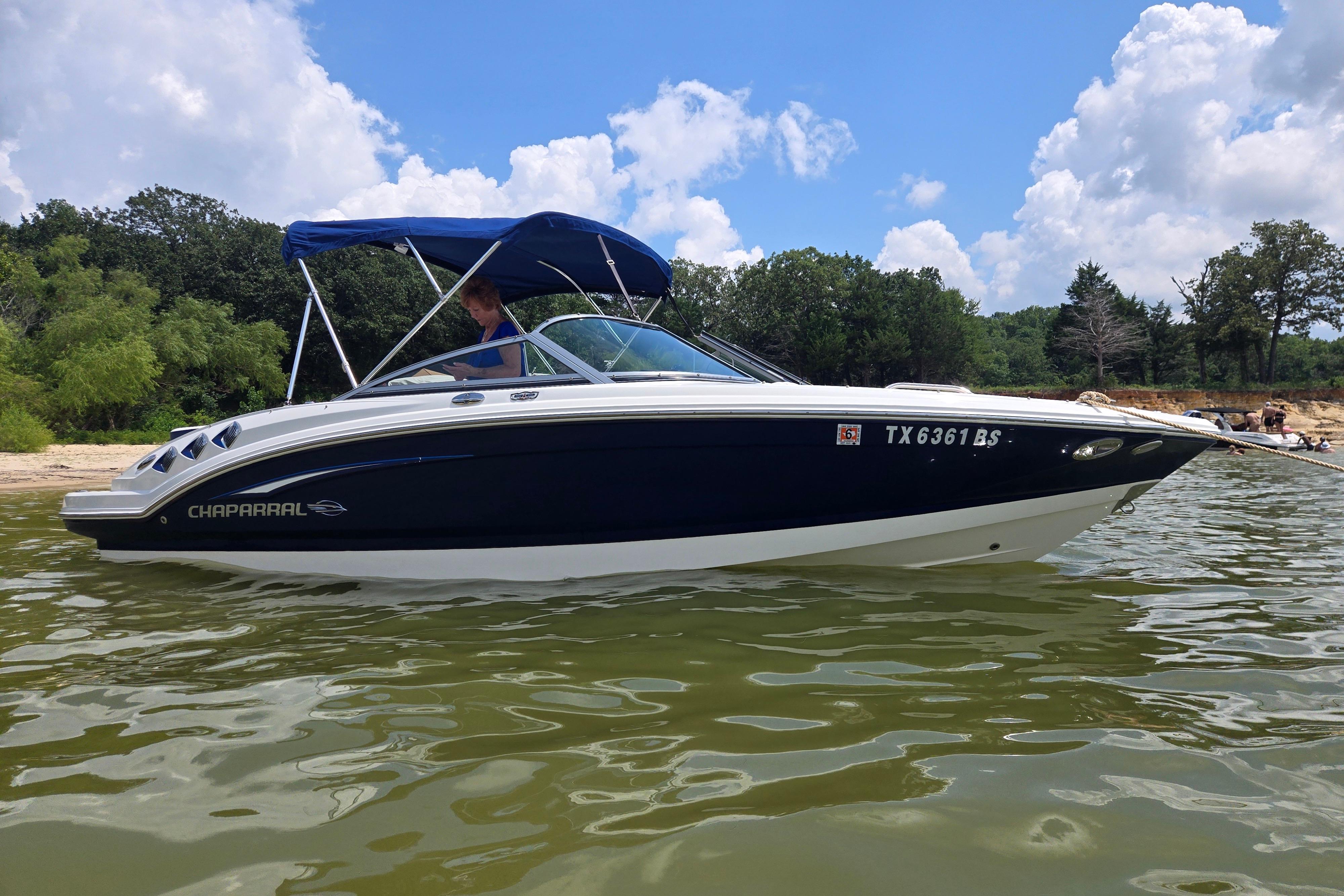 Chaparral 206 SSi 2010 Chaparral 206 SSi boat on a lake with lush greenery and blue sky.
