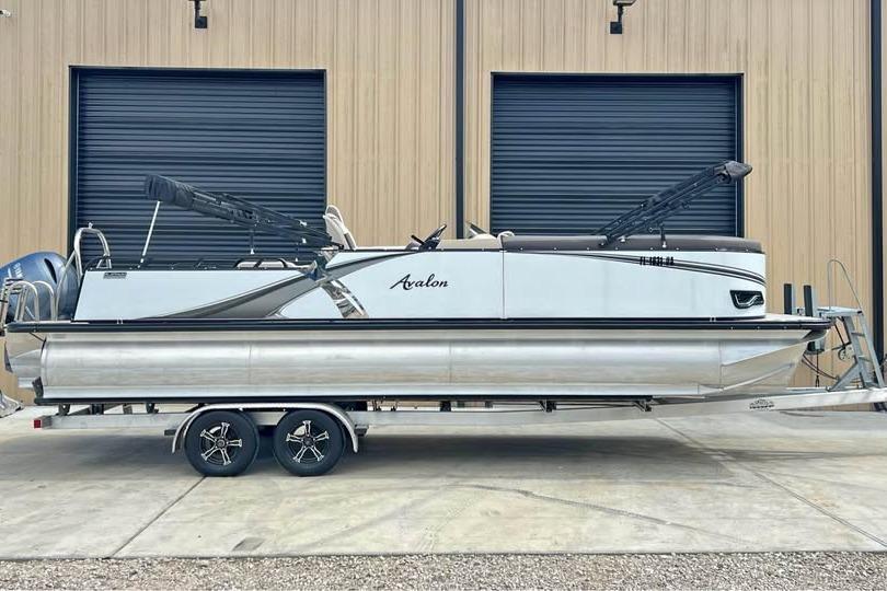 Avalon LSV 2585 2024 Avalon LSV 2585 pontoon boat on trailer, parked outside a building.