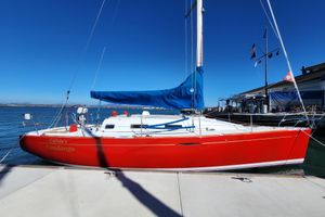 Beneteau First 36.7 Red 2004 Beneteau First 36.7 sailboat docked, blue sail cover, clear sky background.