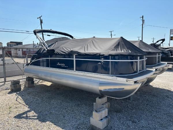 Barletta A22CC 2025 Barletta A22CC pontoon boat covered and elevated on blocks in a storage area.