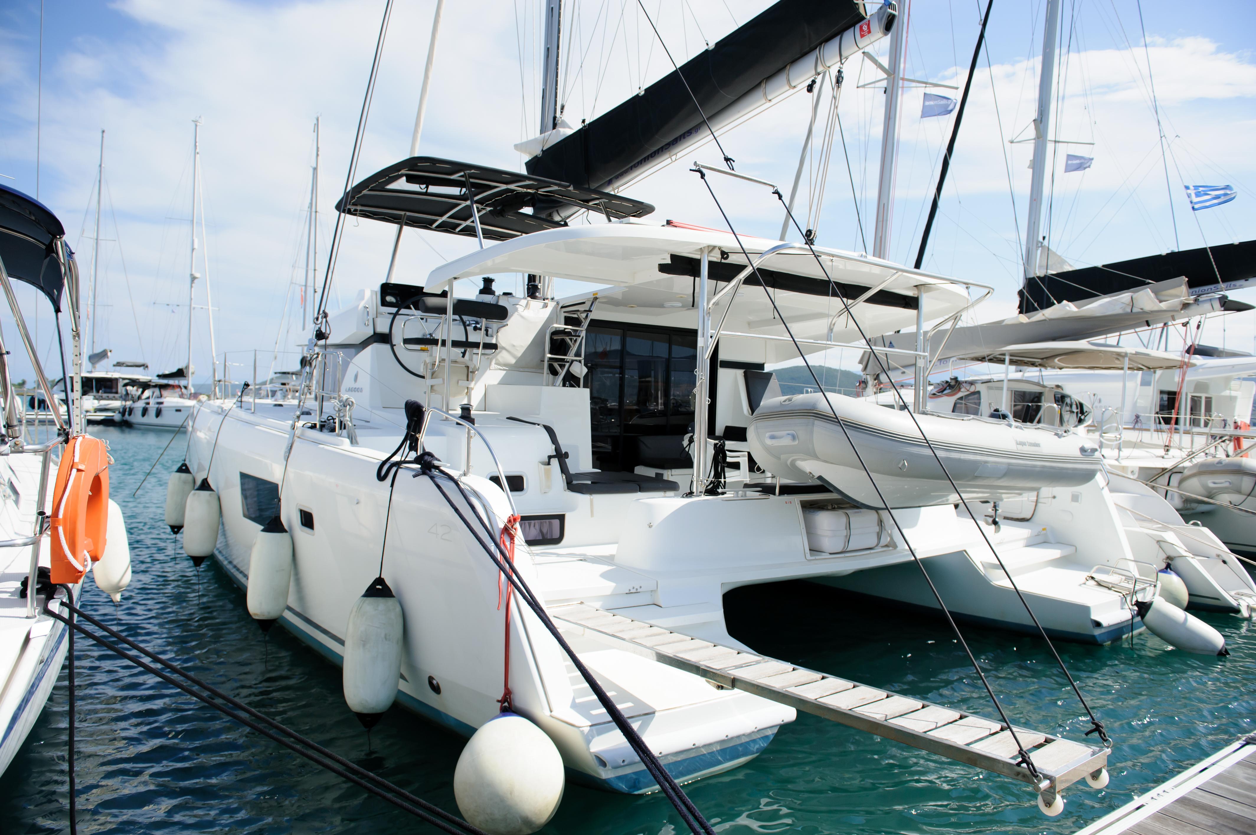 Lagoon 42 2019 Lagoon 42 catamaran docked at marina, featuring sleek design and modern amenities.