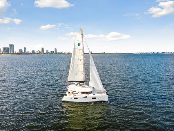 Lagoon 42 Lagoon 42 catamaran sailing on open water with city skyline in the background, 2018 model.