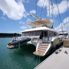 Lagoon 620 Luxury Lagoon 620 catamaran yacht docked at marina, 2011 model, with inflatable boat attached.