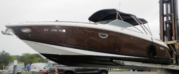 Cobalt 302 2015 Cobalt 302 boat on forklift, brown hull, dockside view.