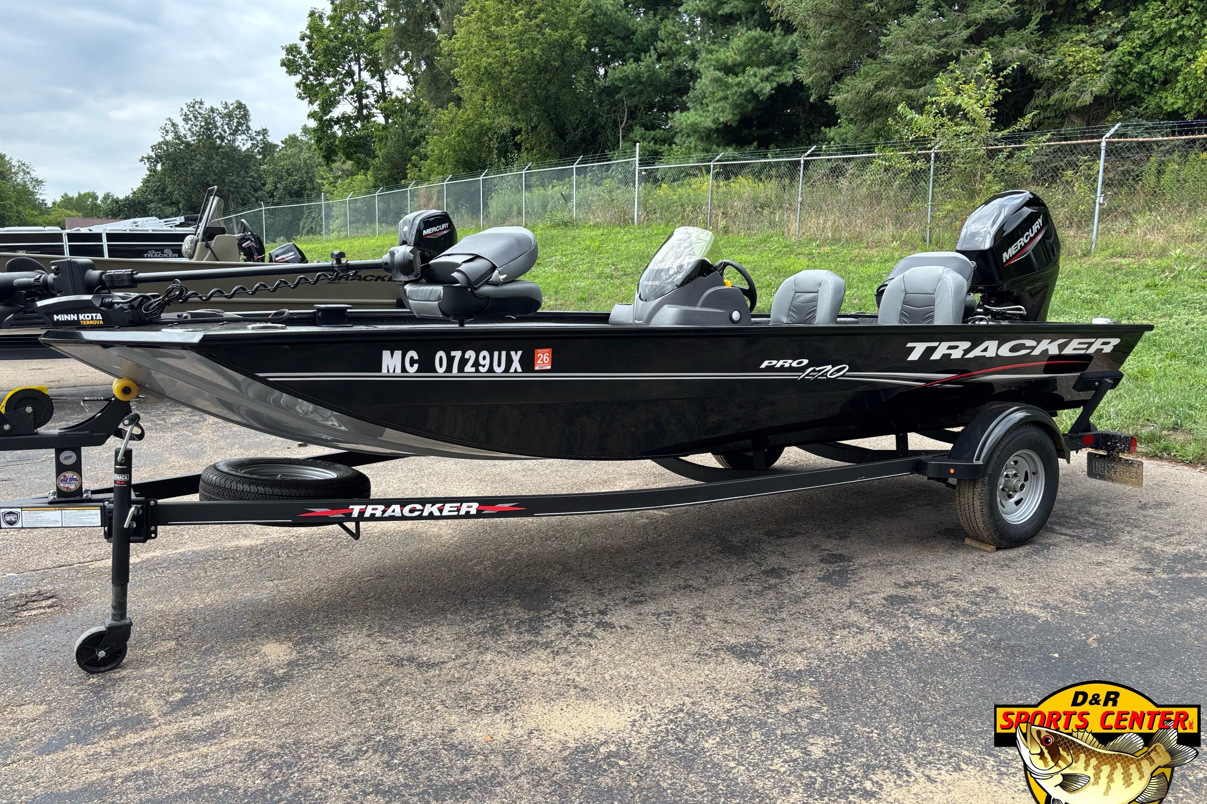 Tracker Pro 170 2023 Tracker Pro 170 boat on trailer, parked outdoors with trees in background.
