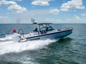 Axopar 28 T-Top Brabus 2022 Axopar 28 T-Top Brabus cruising on open water under a clear blue sky.