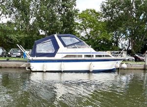 Fairline 32 Phantom 1981 Fairline 32 Phantom boat docked on a calm river, surrounded by trees.