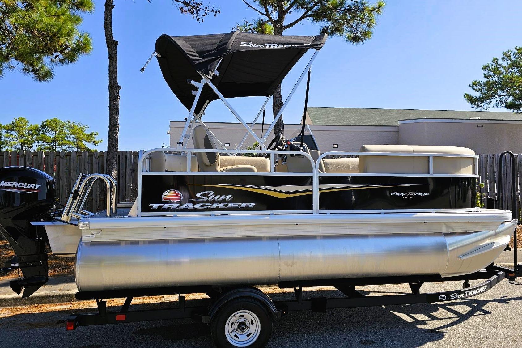 Sun Tracker Party Barge 16 DLX 2025 Sun Tracker Party Barge 16 DLX pontoon boat on trailer, parked outdoors.